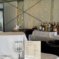 Cocktail bar setup with fairy light backdrop and printed drink menu
