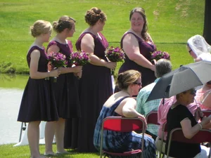 Bridesmaids in purple dresses posed by the pond