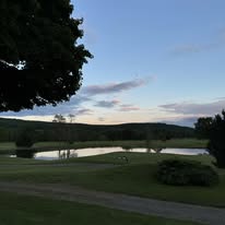 Course at dusk with pond and tree silhouettes
