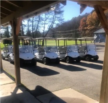 Golf carts lined up along the course with brilliant fall foliage at Genegantslet Golf Club